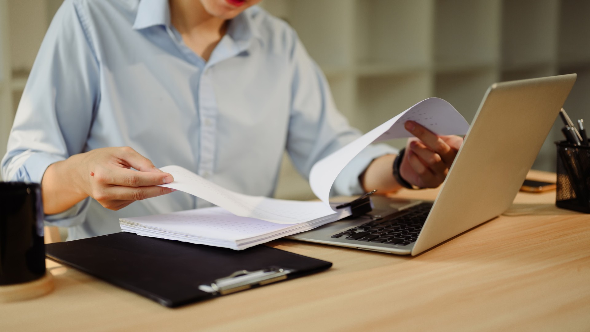 Focused businessman working with laptop and reviewing documents at workspace